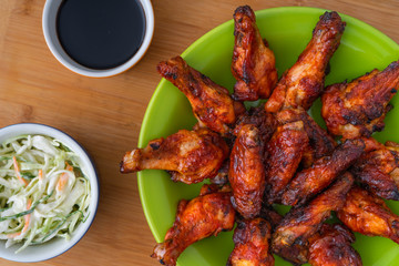 BBQ CHICKEN WINGS, SERVED WITH SALAD OF CABBAGE, IN GREEN PLATE AND YELLOW BACKGROUND