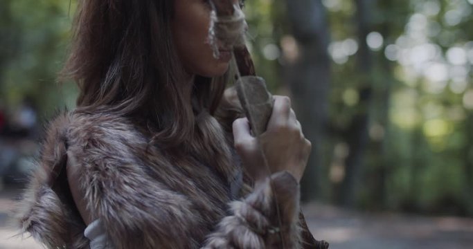 Shot of woman holding weapon cavemen neanderthals wearing animal skin stand beating screaming breasts in prehistoric forest ancient bushman aboriginal evolution stone primitive cave slow motion