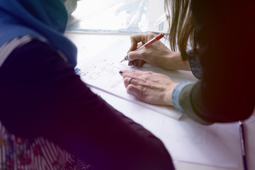 Female Architecture teacher at work. Female professor explain architectural projects to students. Beautiful female university architecture professor explain lessons to multiethnic students.