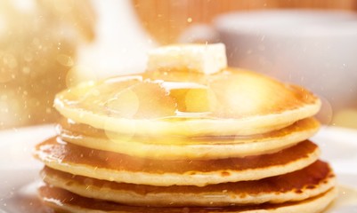 Panckes with butter and syrup with coffee in the background