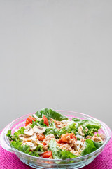 Salad with lettuce, tomato, mushrooms and fish. Pink tablecloth