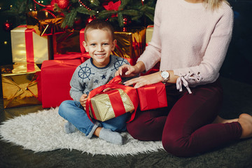 Beautiful mother in a white sweater. Family with cristmas gifts. Little boy near christmas tree