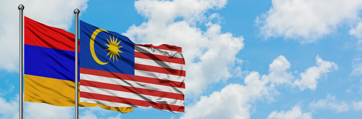 Armenia and Malaysia flag waving in the wind against white cloudy blue sky together. Diplomacy concept, international relations.