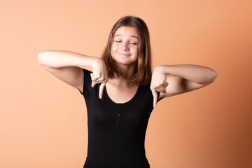 Girl shows a finger down, on a light orange background.
