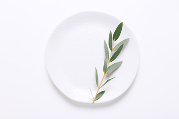 White plate with Eucalyptus leaf on white background, Top view