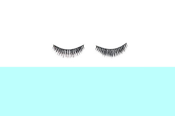 False eyelashes on colorful background, top view