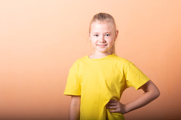 The girl put her hands on her hips, on a light orange background.