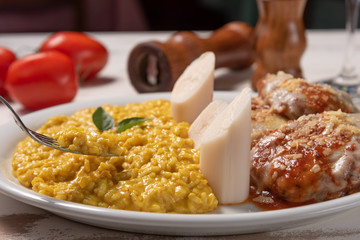 Saffron Risotto with parmigiana steak beef. Risoto and beef in a white plate on wooden white background. Soft light. Italian food. Risotto with curcuma