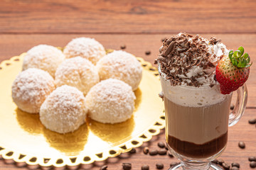 Cold coffee drink frappe (frappuccino), with whipped cream and chocolate nibs, with grains of coffee on wooden background