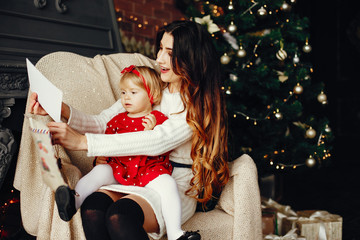 Elegant mother in a white sweater. Family with letter. Little girl near christmas tree