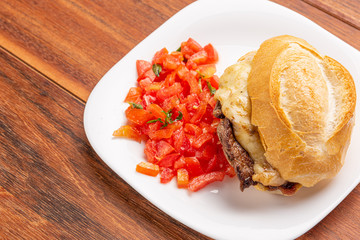 Beef steak sandwich with cheese and tomato, isolated on wooden background