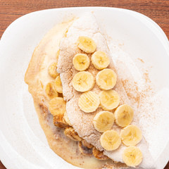 Tapioca filled with banana, cinnamon and condensed milk, on wooden background. Flatbread made from cassava (also known as casabe, bammy, beiju, bob, biju).