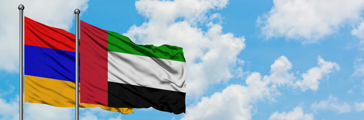 Armenia and United Arab Emirates flag waving in the wind against white cloudy blue sky together. Diplomacy concept, international relations.