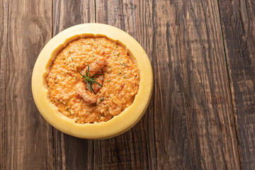 Italian shrimp risotto served inside a big Parmesan Cheese Wheel on a wooden background