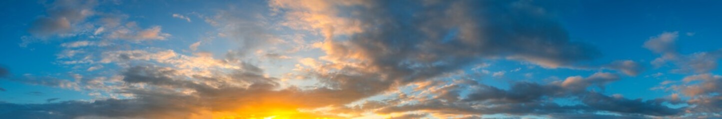 Panorama Sunlight with dramatic sky. Cumulus sunset clouds with sun setting down on dark background.Vivid orange cloud sky.