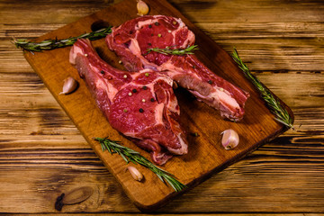 Raw ribeye steak, spices, rosemary and garlic on cutting board