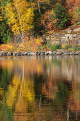 Fototapeta premium rocky shore and autumn colors reflected in water