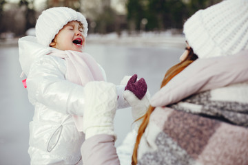 Family have fun in a winter park. Stylish mother in a pink jacket. Little girl in a winter clothes.