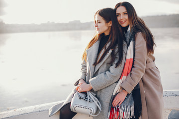 Fashionable girls in a winter city. Stylish ladies in a coats. Women near water