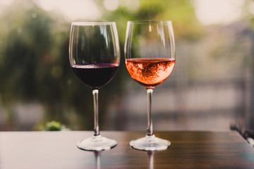 celebrating the moment, couple of glasses with orange cocktail and wine on table with garden bokeh...