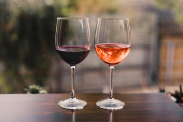 celebrating the moment, couple of glasses with orange cocktail and wine on table with garden bokeh