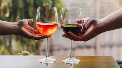 concept of partying and celebrating the moment, couple of glasses with orange cocktail and wine on table with garden bokeh 