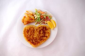 Heart shape Chicken Schnitzel with salad, fried potato wedges