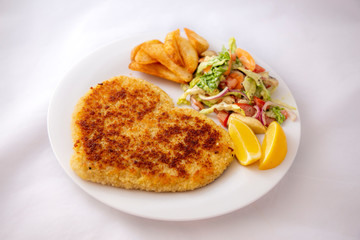 Heart shape Chicken Schnitzel with salad, fried potato wedges