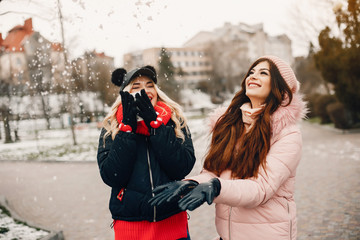 Fashionable girls in a winter city. Stylish ladies in a cute jackets. Girl with cup of coffee