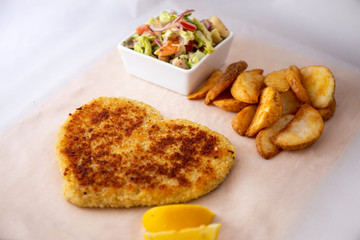 Heart shape Chicken Schnitzel with salad, fried potato wedges