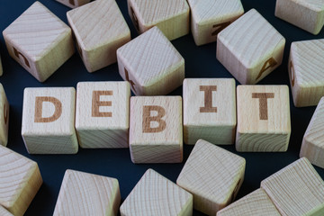 Debit, money or cash that people can pay to buy consume product concept, cube wooden block with alphabet combine the word Debit on black chalkboard background