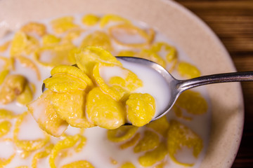Ceramic plate with cornflakes and milk on a wooden table. Healthy eating