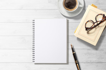 空白のノート、コーヒー、本、万年筆のある白木のテーブル