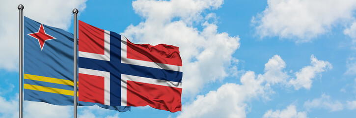 Aruba and Norway flag waving in the wind against white cloudy blue sky together. Diplomacy concept, international relations.