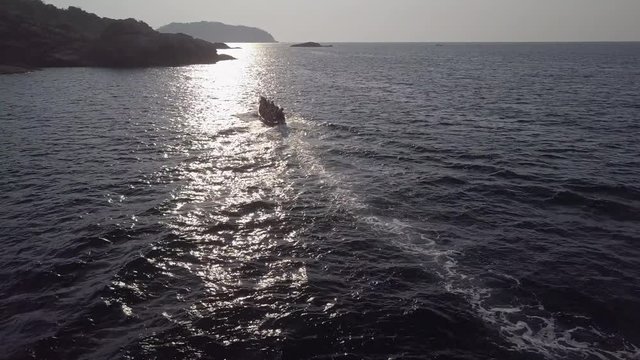 Refugee motor boat in the waves of a sea, crowded and full of escaping people. Going closer to the shore or land
