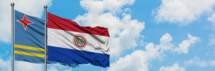 Aruba and Paraguay flag waving in the wind against white cloudy blue sky together. Diplomacy concept, international relations.