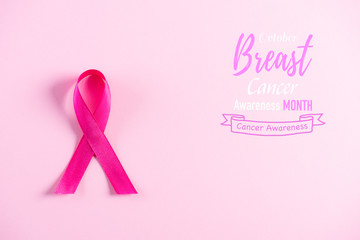 Pink ribbon on pink pastel paper background for supporting breast cancer awareness month campaign.