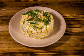 Salad with crab sticks, boiled eggs and cucumbers on a ceramic plate