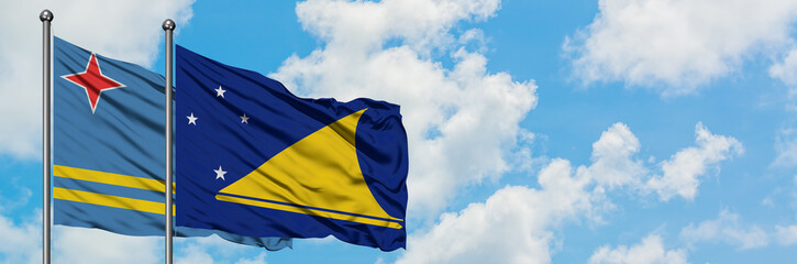 Aruba and Tokelau flag waving in the wind against white cloudy blue sky together. Diplomacy concept, international relations.