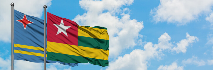 Aruba and Togo flag waving in the wind against white cloudy blue sky together. Diplomacy concept, international relations.