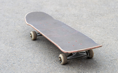 Old cracked gray skateboard on asphalt. View from above.