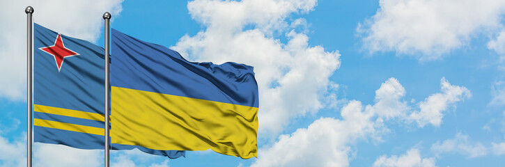 Aruba and Ukraine flag waving in the wind against white cloudy blue sky together. Diplomacy concept, international relations.