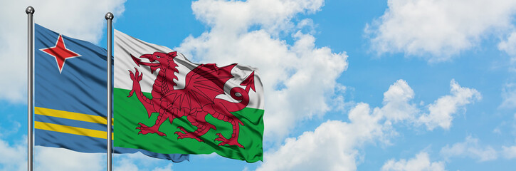 Aruba and Wales flag waving in the wind against white cloudy blue sky together. Diplomacy concept, international relations.