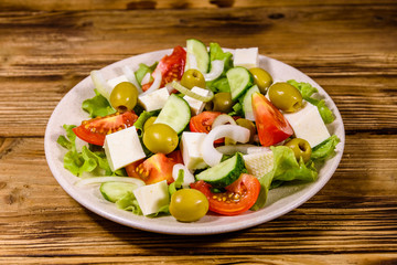 Ceramic plate with greek salad on wooden table
