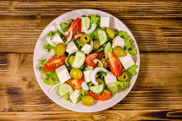 Ceramic plate with greek salad on wooden table. Top view