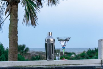 cocktail glass and shaker on the beach with palm tree