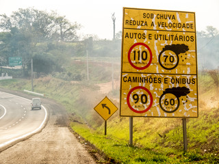 Signpost indicating speed limit on dry and wet roads on Comandante João Ribeiro de Barros Highway, SP 294, near the entrance of Jafa district, in Garca municipality