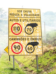 Signpost indicating speed limit on dry and wet roads on Comandante João Ribeiro de Barros Highway, SP 294, near the entrance of Jafa district, in Garca municipality