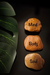 Obraz na płótnie Canvas Zen Concept: Mind, Body and Soul wordings on stones against black background 