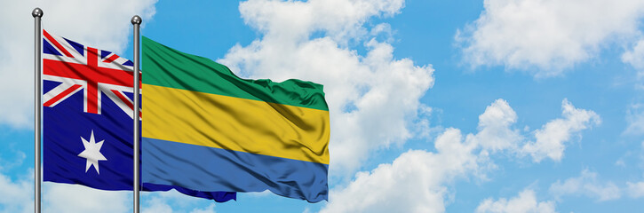 Australia and Gabon flag waving in the wind against white cloudy blue sky together. Diplomacy...